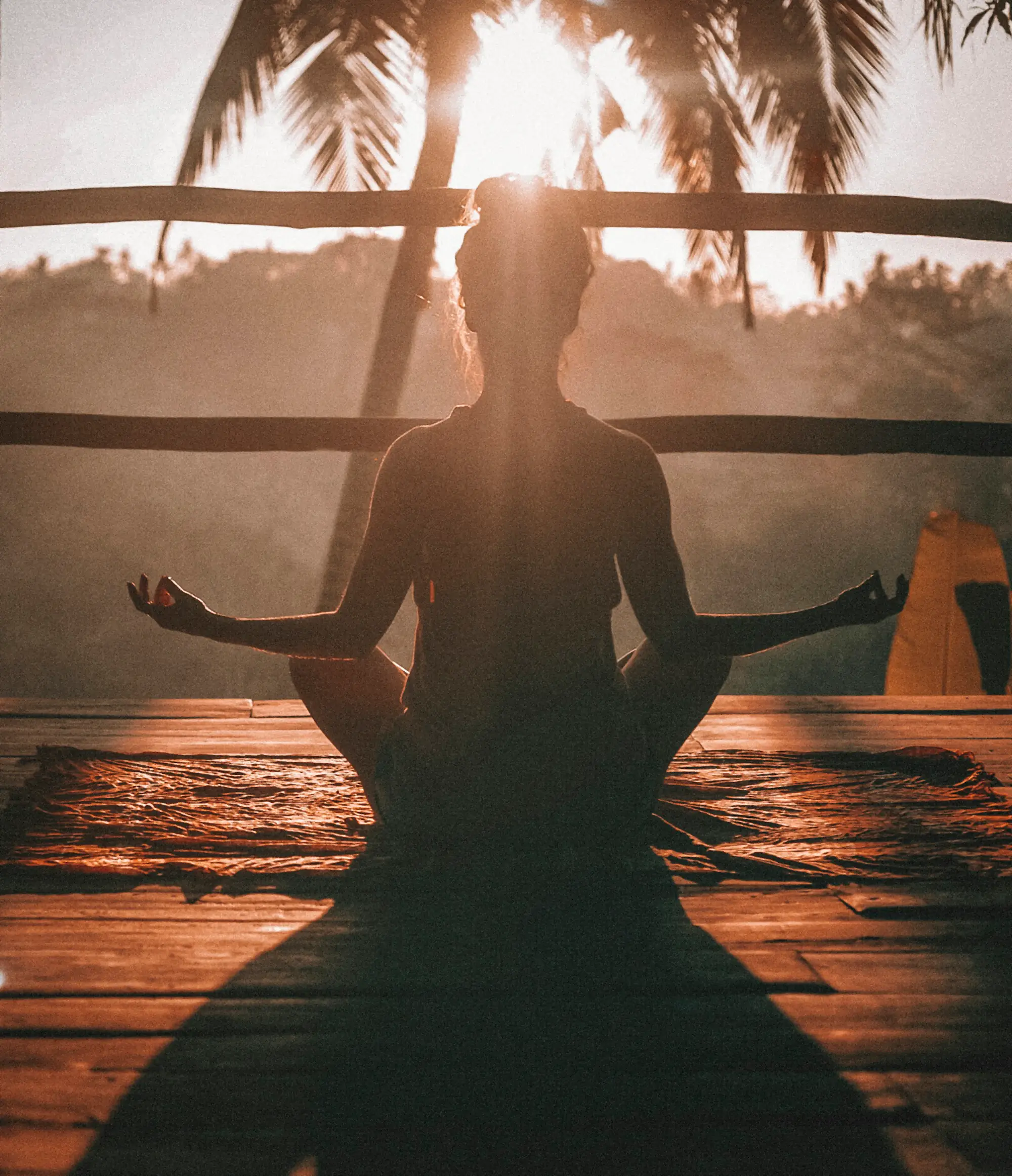 Person meditating by a window at sunset