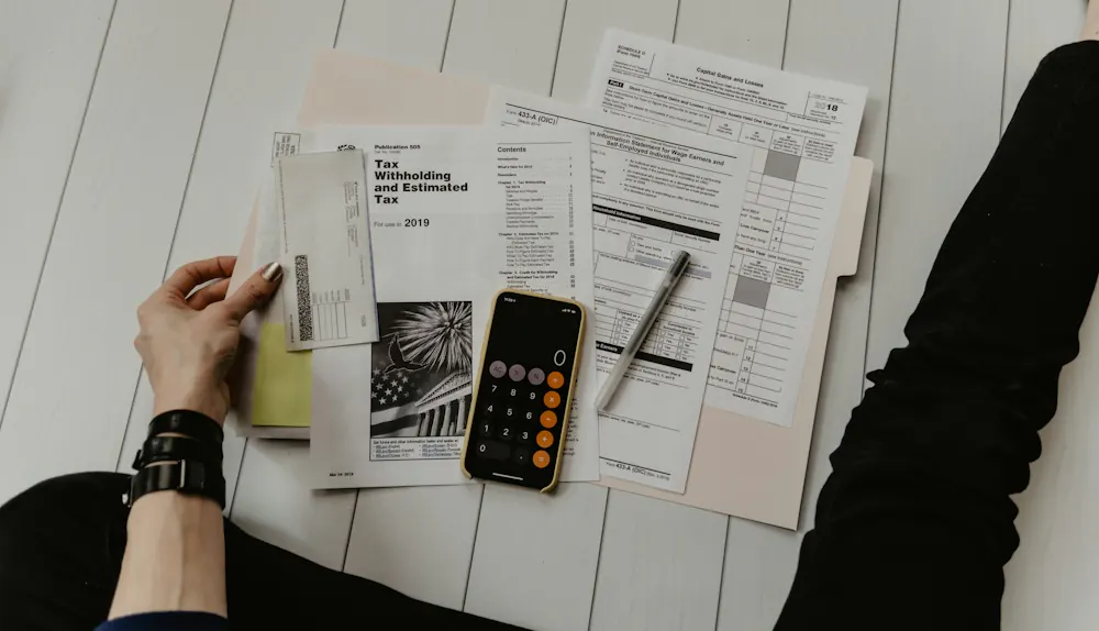Person working through figures with a calculator and paperwork