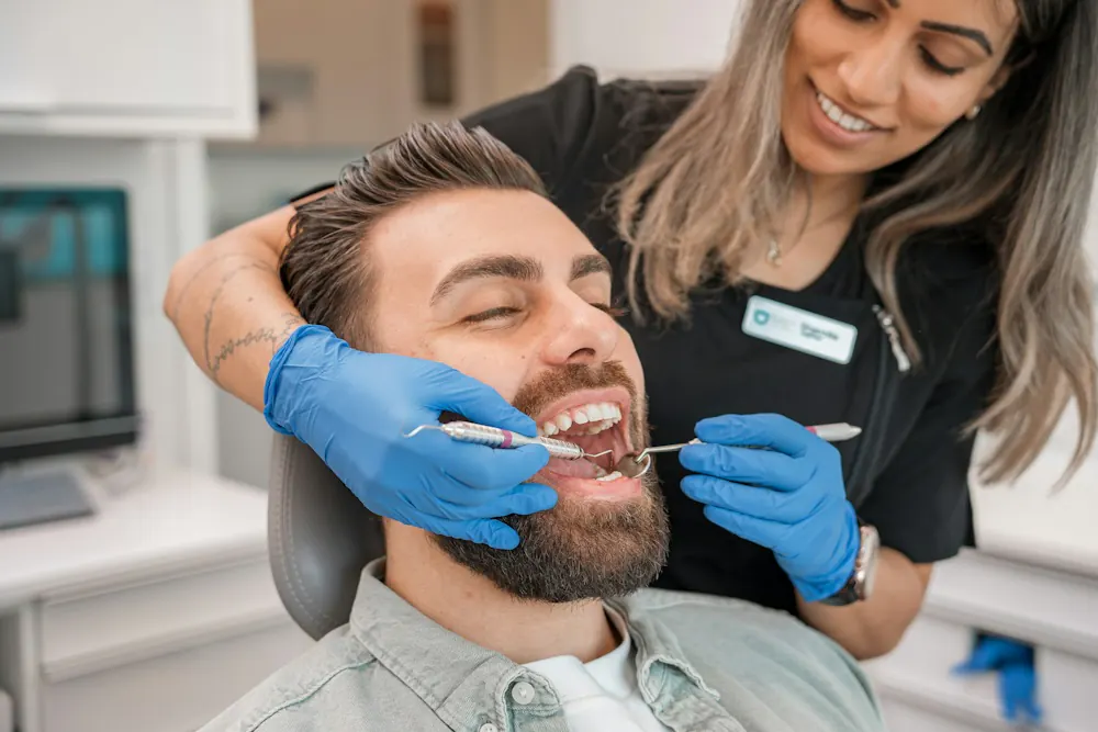 Dentist in blue gloves examining a patient’s teeth